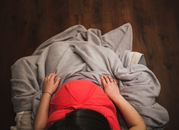 Pregnant person sitting in a chair with a blanket on their lap